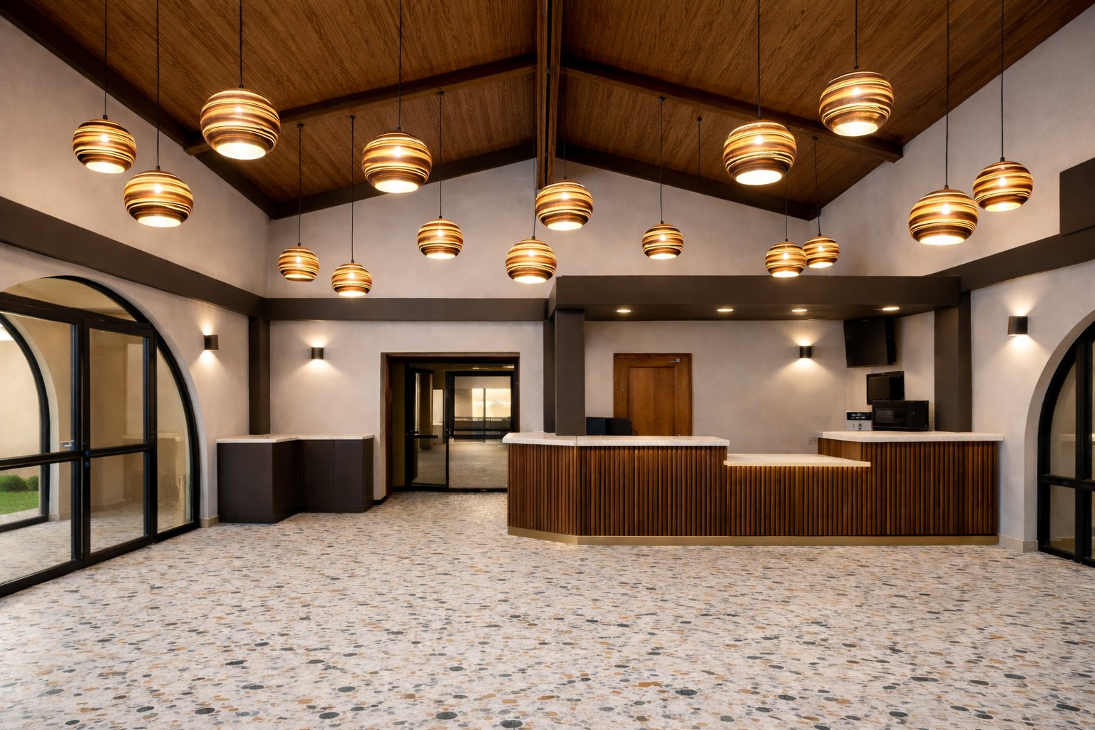 The Hotel Embarque lobby, with a wood-clad reception desk, arched windows and gold pendant lighting
